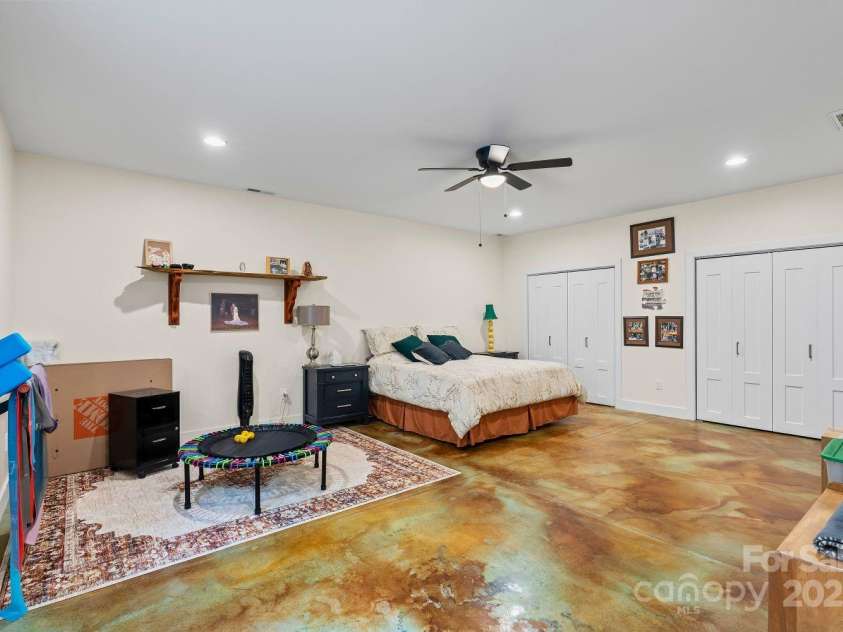 143 Burnside Trail, Hendersonville, NC 28792.  MLS# CAR4258291, YatesRealty ID 23895. Downstairs: second ensuite bedroom with dramatic insulated and acid-finished concrete floor, and double closets.