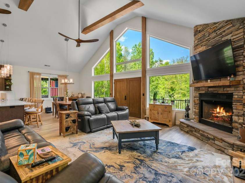 143 Burnside Trail, Hendersonville, NC 28792.  MLS# CAR4258291, YatesRealty ID 23895. Spectacular great room anchored by stone fireplace with custom mantle made from reclaimed wood on property.