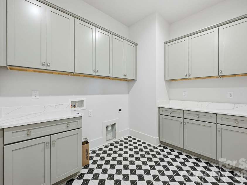 7245 Westrow Avenue, Charlotte, NC 28278.  MLS# CAR4314661, YatesRealty ID 2395. Thoughtfully designed laundry room featuring added upper and lower cabinetry for storage and organization. The decorative tile flooring adds a stylish touch. Generous layout for folding and everyday convenience. 