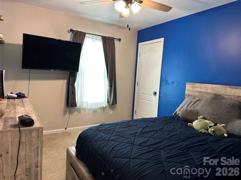 1309 Red Birch Place, Kannapolis, NC 28081.  MLS# CAR4373489, YatesRealty ID 24037. Bright and comfortable secondary bedroom featuring a bold accent wall, ceiling fan, and great natural light. Offers ample space for a bed, dresser, or desk—perfect for guests, family, or a home office.