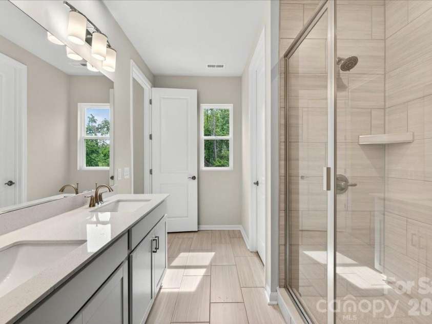6049 Longar Lane, Charlotte, NC 28269.  MLS# CAR4384836, YatesRealty ID 24079. Light filled bathroom with tree-lined views for added privacy 