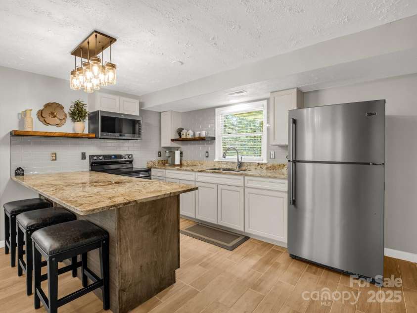 4075 Little River Road, Hendersonville, NC 28739.  MLS# CAR4243668, YatesRealty ID 24087. Lower level full kitchen with breakfast bar, tile flooring, separate exterior entrance