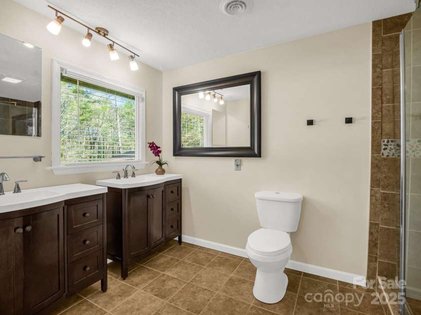 4075 Little River Road, Hendersonville, NC 28739.  MLS# CAR4243668, YatesRealty ID 24087. Primary bedroom's en suite bath with double vanity & tiled/glass shower
