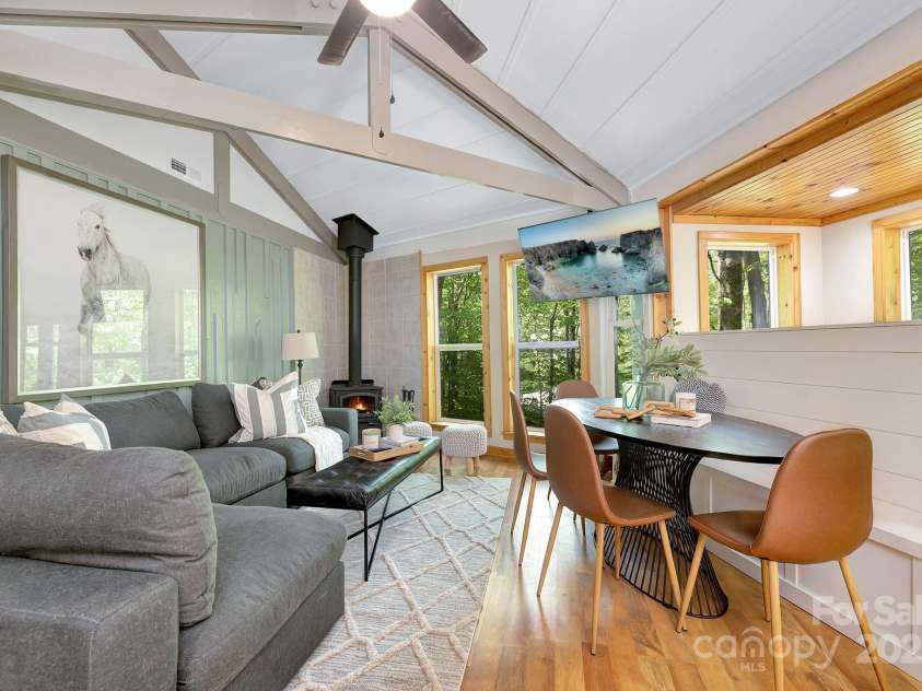 125 Pond Creek Road, Beech Mountain, NC 28604.  MLS# CAR4275348, YatesRealty ID 24128. Sunlit vaulted living area with expansive windows and cozy wood-burning stove