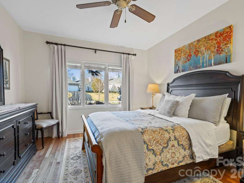 24 Country Meadows Lane, Hendersonville, NC 28792.  MLS# CAR4336584, YatesRealty ID 2420. Comfortable secondary bedroom with hardwood flooring, ceiling fan, and window views that bring in natural light