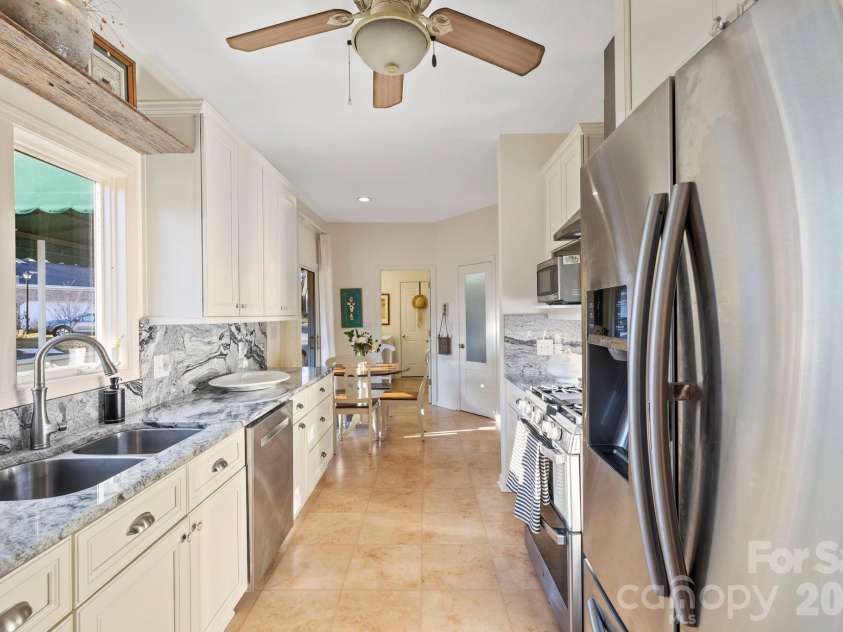24 Country Meadows Lane, Hendersonville, NC 28792.  MLS# CAR4336584, YatesRealty ID 2420. Galley-style kitchen offering abundant counter space, stainless steel appliances, tile flooring, and a practical layout for efficient meal preparation
