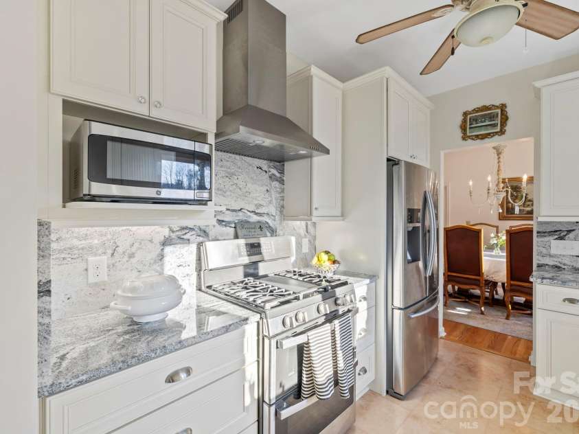 24 Country Meadows Lane, Hendersonville, NC 28792.  MLS# CAR4336584, YatesRealty ID 2420. Updated kitchen with white cabinetry, granite countertops, stainless steel appliances, and a gas range, combining style and functionality