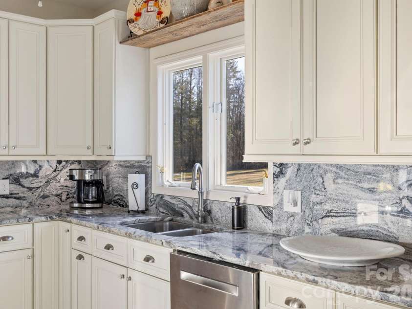 24 Country Meadows Lane, Hendersonville, NC 28792.  MLS# CAR4336584, YatesRealty ID 2420. Well-appointed kitchen workspace with granite counters, tile backsplash, ample cabinetry, and a window that brings in natural light