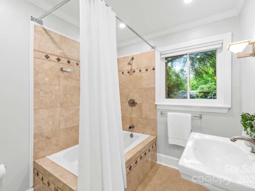 4114 Stacy Boulevard, Charlotte, NC 28209.  MLS# CAR4258425, YatesRealty ID 24208. Bright bathroom with detailed tiled shower and a pedestal sink, perfect for a tranquil bathroom experience.
