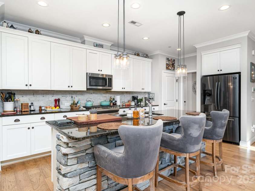 3899 Zemosa Lane, Concord, NC 28027.  MLS# CAR4275282, YatesRealty ID 24226. Chef's kitchen with a large island, decorated with stone similar to the front of the home.