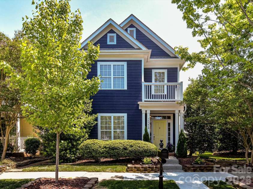 15224 Waterfront Drive, Huntersville, NC 28078.  MLS# CAR4374936, YatesRealty ID 24231. Charming two-story home with classic curb appeal, featuring a welcoming front porch, balcony, lush landscaping, and a beautifully maintained exterior in a serene, tree-lined setting.