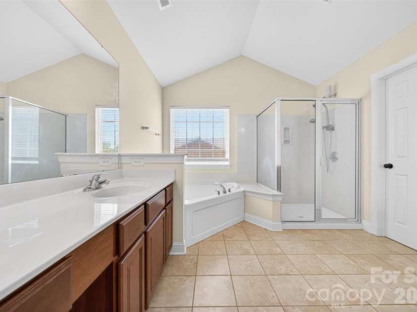 1008 Spring Rose Lane, Matthews, NC 28104.  MLS# CAR4382906, YatesRealty ID 24258. Primary bath featuring vaulted ceiling, dual vanities, and spacious layout designed for comfort and convenience.
