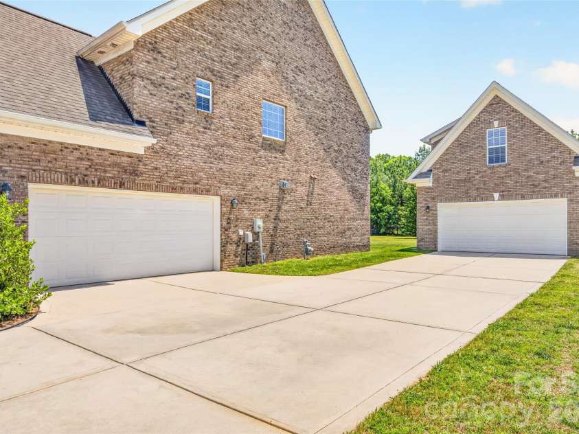 1008 Spring Rose Lane, Matthews, NC 28104.  MLS# CAR4382906, YatesRealty ID 24258. Side elevation showcasing attached 2 car garage and detached 2 car garage with finished flex space above and additional full bathroom.