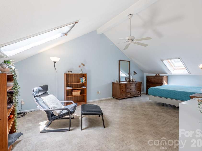 12 Pencross Circle, Etowah, NC 28729.  MLS# CAR4372034, YatesRealty ID 24339. View of the upper-level bedroom from the bonus/flex space. Note two openable skylights and a ceiling fan. The efficient mini-split is installed on the wall just beyond the bookcase to the left. 