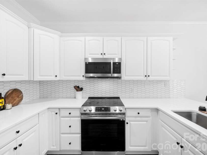 21012 Entrada Drive, Cornelius, NC 28031.  MLS# CAR4382641, YatesRealty ID 24611. Kitchen makeover with a modern feel – quartz countertops, designer tile backsplash, farmhouse sink, stainless steel appliances, breakfast bar, and it opens up nicely to the dining area.