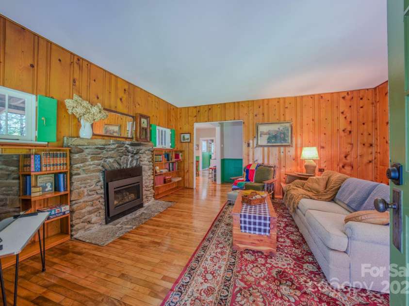 7 Bachelder Lane, Candler, NC 28715.  MLS# CAR4271857, YatesRealty ID 24801. Cozy living room with original knotty pine paneling and fieldstone fireplace