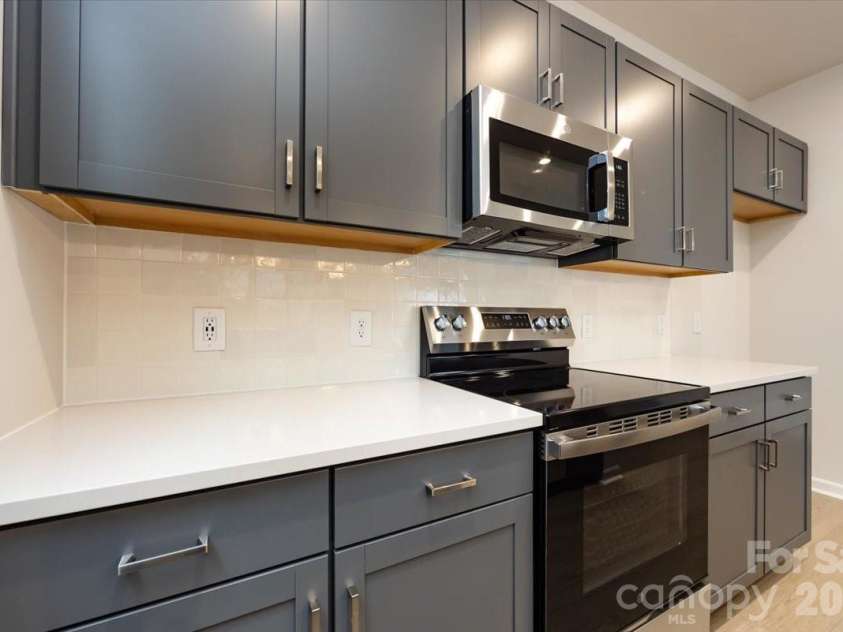 6017 Longar Lane, Charlotte, NC 28269.  MLS# CAR4356792, YatesRealty ID 24944. Kitchen with rich grey cabinets with white quartz countertops