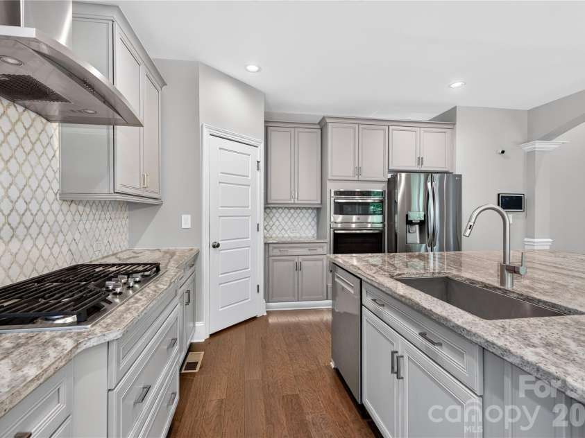 137 Trelawn Street, Fort Mill, SC 29715.  MLS# CAR4371726, YatesRealty ID 24962. Kitchen features a gas cooktop, double convection oven and microwave, stainless steel appliances, and a tile backsplash.