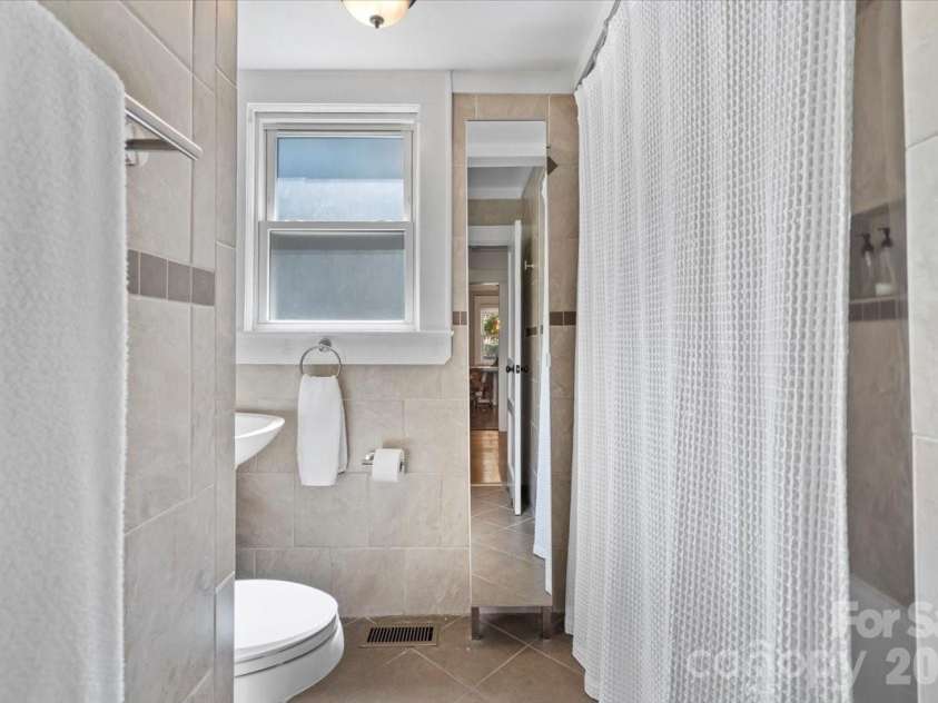 904 Academy Street, Charlotte, NC 28205.  MLS# CAR4380791, YatesRealty ID 25069. Bathroom with natural light, tile to the ceiling, pedestal sink, smartly placed storage with a full length mirror and tub/shower with a shampoo nook