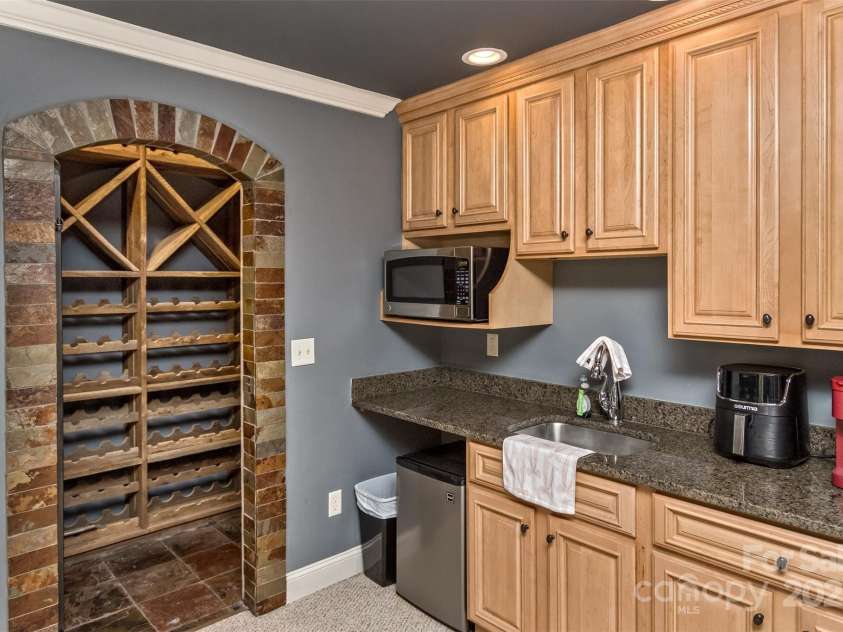 33 Stone House Road, Arden, NC 28704.  MLS# CAR4261250, YatesRealty ID 25362. Custom wine cave in the lower level with kitchenette and wet bar beverage center