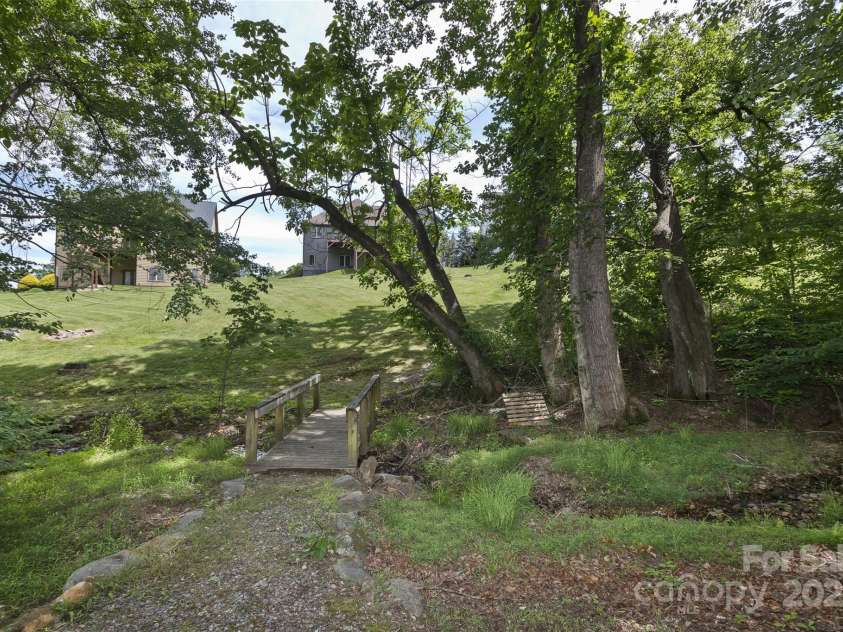 33 Stone House Road, Arden, NC 28704.  MLS# CAR4261250, YatesRealty ID 25362. Gentle creek in the common area behind the home.  Leads to the walking trail. No damage from Helene.