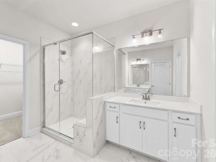 10141 Rainier Trail Drive, Huntersville, NC 28078.  MLS# CAR4375749, YatesRealty ID 25370. Description of the primary ensuite bathroom: Spa-like, luxurious primary ensuite designed with premium finishes. It features beautiful marbled tile throughout, complemented by sleek quartz countertops. The spa