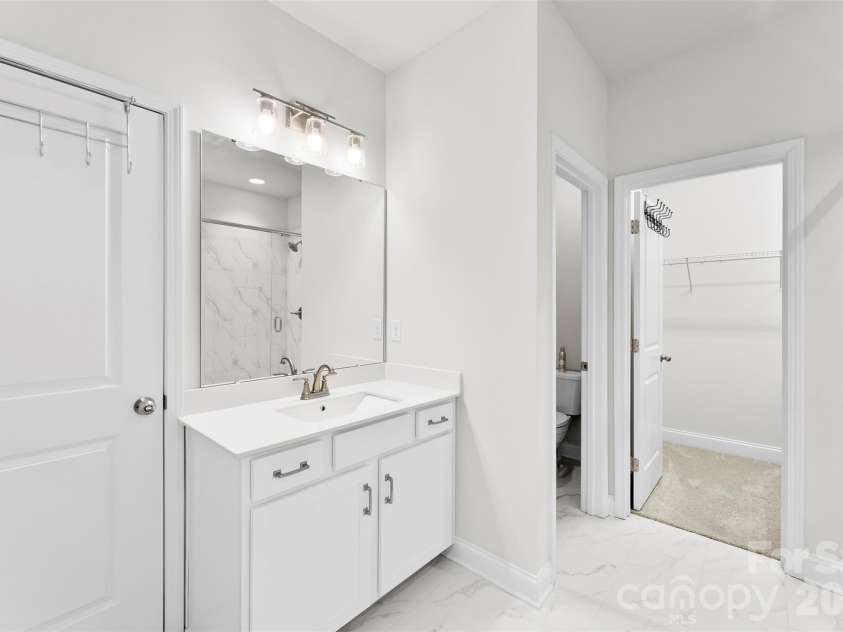 10141 Rainier Trail Drive, Huntersville, NC 28078.  MLS# CAR4375749, YatesRealty ID 25370. The second vanity located within the primary ensuite bathroom boasts a contemporary design, highlighted by a rectangular sink, a durable and elegant quartz countertop, and thoughtfully integrated, ample storag