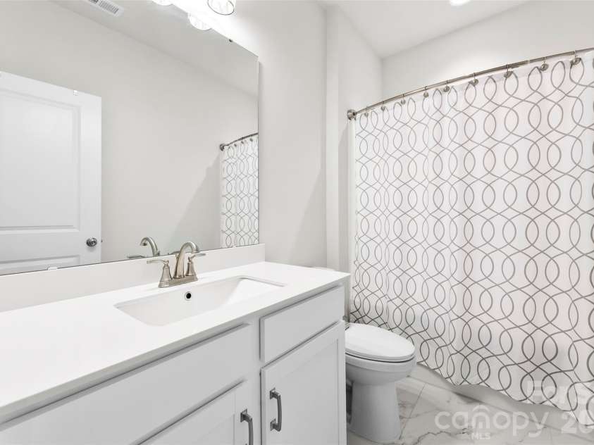10141 Rainier Trail Drive, Huntersville, NC 28078.  MLS# CAR4375749, YatesRealty ID 25370. This secondary bathroom is a truly exceptional space, offering a complete and luxurious experience. It features generously sized quartz countertops that provide ample surface area, complemented by a stylish re