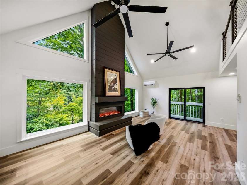 81 Summer Trees Lane, Burnsville, NC 28714.  MLS# CAR4417537, YatesRealty ID 25389. Spacious living area featuring a custom electric fireplace, expansive forest views, and direct access to the private deck.