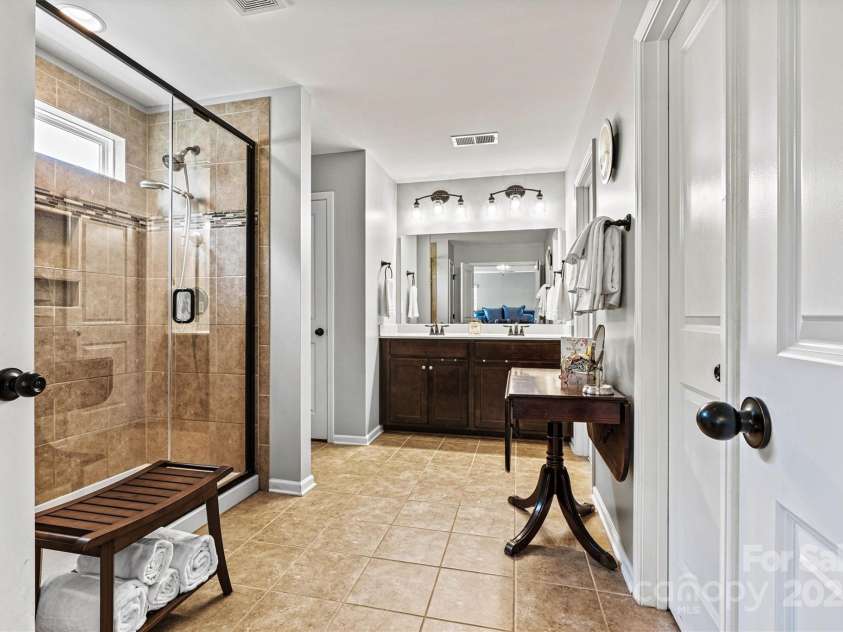 112 Heart Pine Lane, Statesville, NC 28677.  MLS# CAR4271076, YatesRealty ID 25527. Rench doors open to a spa-like retreat featuring tile floors, a spacious walk-in tiled shower with decorative listello accent, a handheld showerhead, and a transom window that fills the space with natural light.