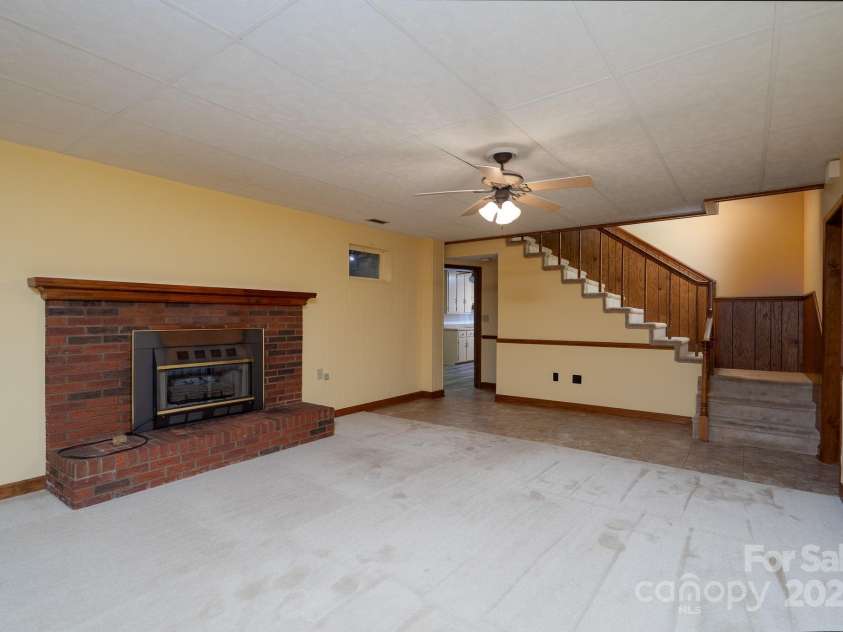 614 Azalea Lane, China Grove, NC 28023.  MLS# CAR4280599, YatesRealty ID 25550. Bonus room in basement. Fireplace has gas logs but not connected to fuel source at this time. Bedroom and bathroom off to the right. Hallway to laundry (mud room) and walk out door to the driveway.