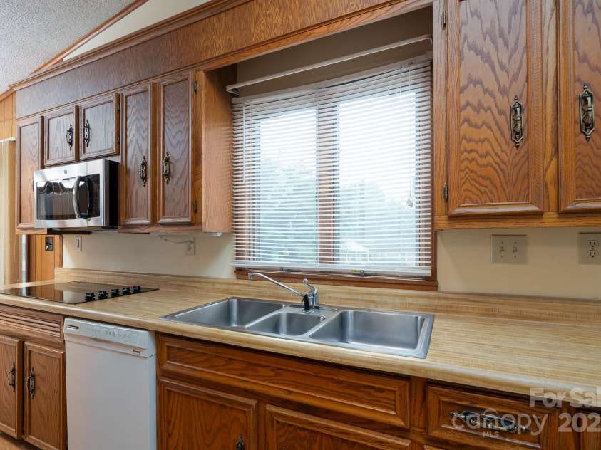 614 Azalea Lane, China Grove, NC 28023.  MLS# CAR4280599, YatesRealty ID 25550. Kitchen has dishwasher and built in microwave unit. Electric stovetop is located below the microwave. Oven out of view to the left.