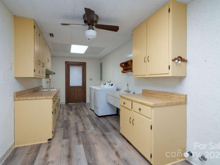 614 Azalea Lane, China Grove, NC 28023.  MLS# CAR4280599, YatesRealty ID 25550. Laundry (mud room) with wash bay, electric dryer hook up. and connection for refrigerator. Electric stove top on the countertop to the left with lots of cabinet storage. Walk out door leads to the driveway. This is consi