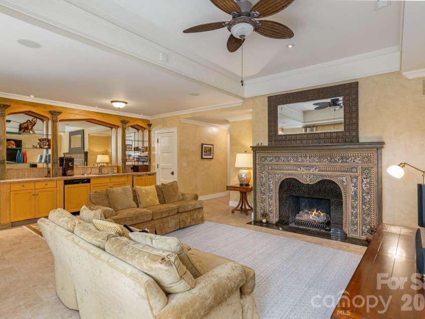 8 Fairway Place, Asheville, NC 28803.  MLS# CAR4245541, YatesRealty ID 2564. At the heart of the lower level lies a spacious rec room, anchored by a striking stone fireplace that radiates warmth and charm. 