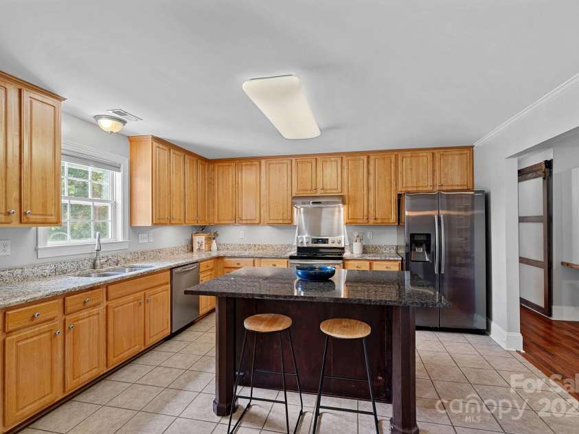 7478 Pine Ridge Drive, Denver, NC 28037.  MLS# CAR4272908, YatesRealty ID 25697. Kitchen with tile flooring, granite countertops, and an island with seating for two.