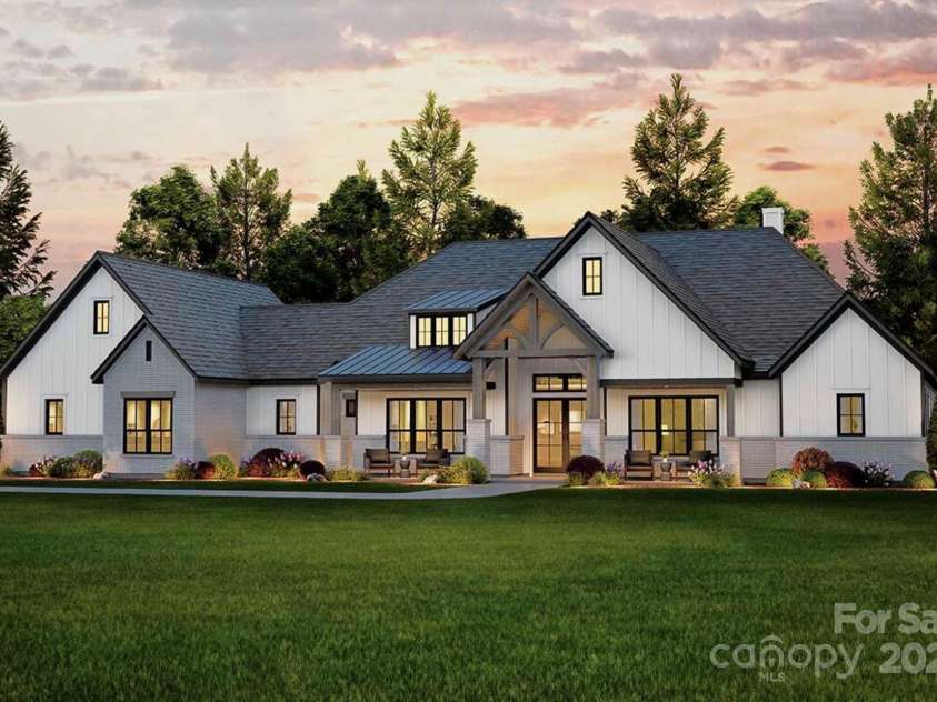 Lot 4 Country Estates Drive, Waxhaw, NC 28173.  MLS# CAR4278303, YatesRealty ID 25767. This stunning modern farmhouse features a crisp white exterior with board-and-batten siding, contrasting dark trim, and a welcoming covered front porch accented by timber beams and brick columns.