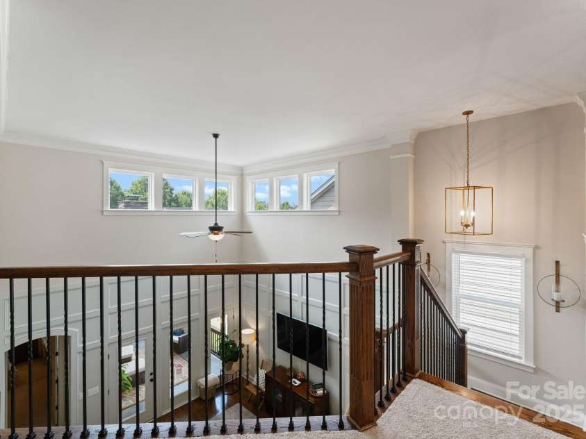 5137 Rialto Street, Belmont, NC 28012.  MLS# CAR4277416, YatesRealty ID 25831. The second floor offers a captivating overlook of the grand great room below, enhancing the home’s open and airy design. This vantage point allows natural light from the soaring two-story ceilings and upper-level windows 