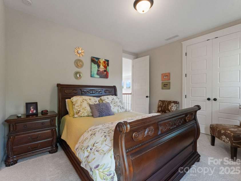 5137 Rialto Street, Belmont, NC 28012.  MLS# CAR4277416, YatesRealty ID 25831. This generously proportioned upstairs bedroom exudes refined elegance and tranquility. Brightened by natural light, it features graceful French doors that open onto a charming covered porch, offering a serene outdoor esca