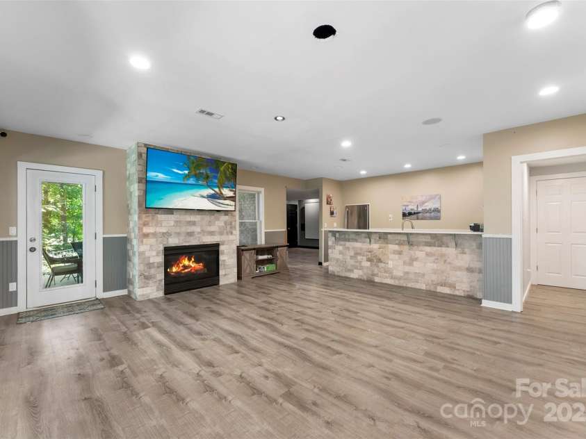 10007 Hillspring Drive, Huntersville, NC 28078.  MLS# CAR4272682, YatesRealty ID 25864. Lower level boasts durable LVP flooring throughout, featuring a cozy fireplace, wet bar, and dining bay—ideal for family gatherings or extended family living