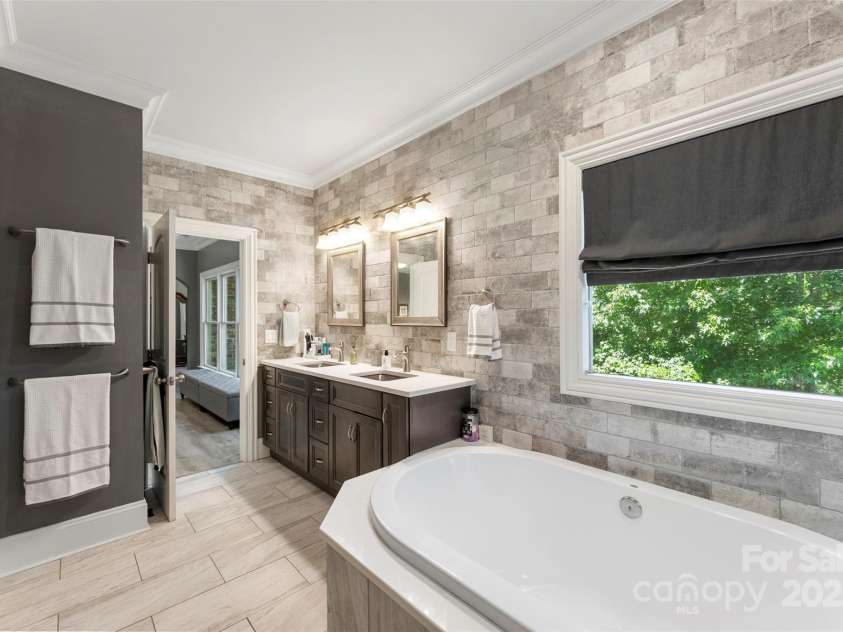 10007 Hillspring Drive, Huntersville, NC 28078.  MLS# CAR4272682, YatesRealty ID 25864. Luxurious primary bath featuring a garden tub overlooking peaceful woods