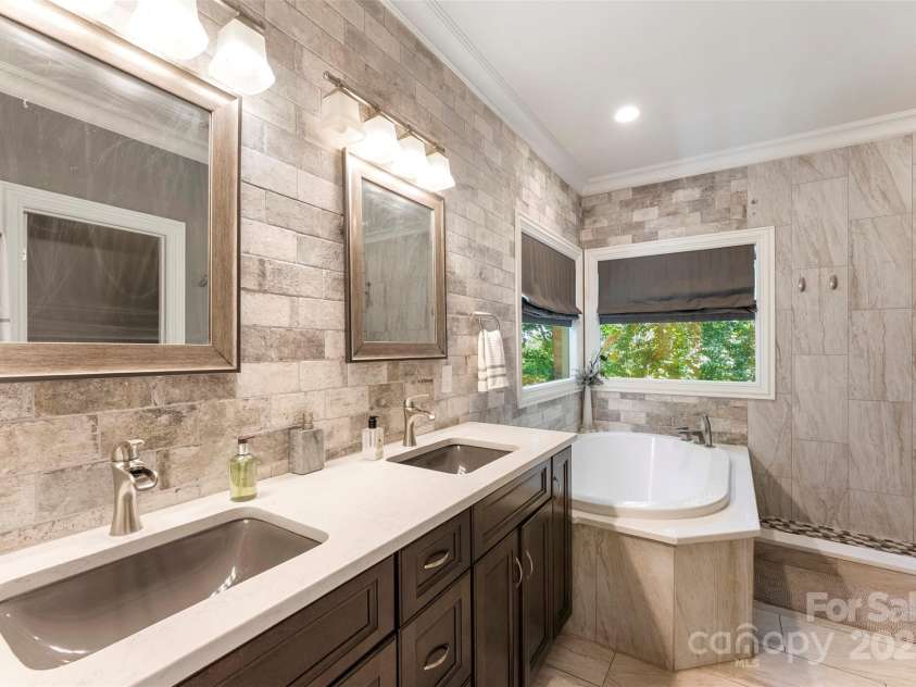10007 Hillspring Drive, Huntersville, NC 28078.  MLS# CAR4272682, YatesRealty ID 25864. Spa-inspired primary bath with a garden tub facing a private wooded area, walk-in tile shower, and quartz countertop dual vanities