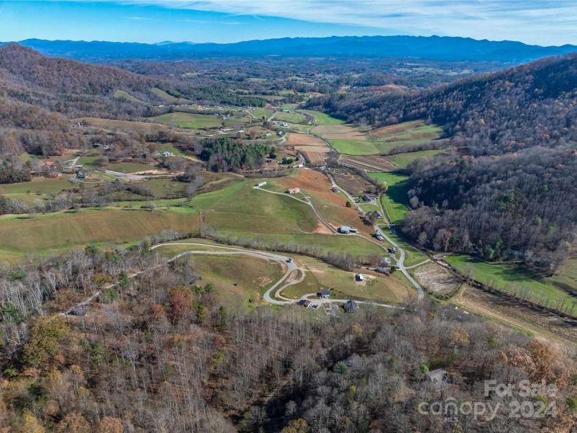 435 N Turkey Creek Road, Leicester, NC 28748.  MLS# CAR4199119, YatesRealty ID 262. View from the back, north western ridge of the property looking down at the homestead, and the eastern flowing valley.  The Black Mountains in the background