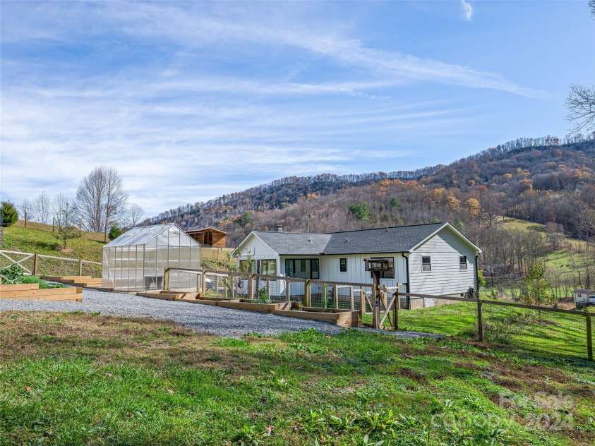 435 N Turkey Creek Road, Leicester, NC 28748.  MLS# CAR4199119, YatesRealty ID 262. View from the backyard of main house looking at fenced garden area and greenhouse.