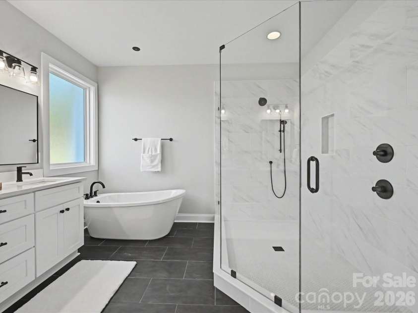 163 Lone Pine Road, Statesville, NC 28625.  MLS# CAR4383652, YatesRealty ID 26311. Luxurious primary bath features dual vanities, a freestanding soaking tub, and an oversized tiled walk-in shower with sleek modern finishes.