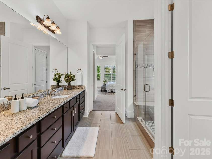 13003 Riley Grace Lane, Cornelius, NC 28031.  MLS# CAR4418120, YatesRealty ID 26526. Spacious primary bath features a long dual-sink granite vanity, tiled walk-in shower, and separate water closet.