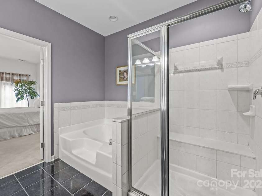 10217 Linksland Drive, Huntersville, NC 28078.  MLS# CAR4281355, YatesRealty ID 26573. Main floor primary bathroom features a step-in shower with tile surround and bench seating.