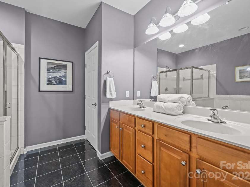 10217 Linksland Drive, Huntersville, NC 28078.  MLS# CAR4281355, YatesRealty ID 26573. Main floor primary bathroom features: expansive double sink vanity with storage below, private WC, tile floors.