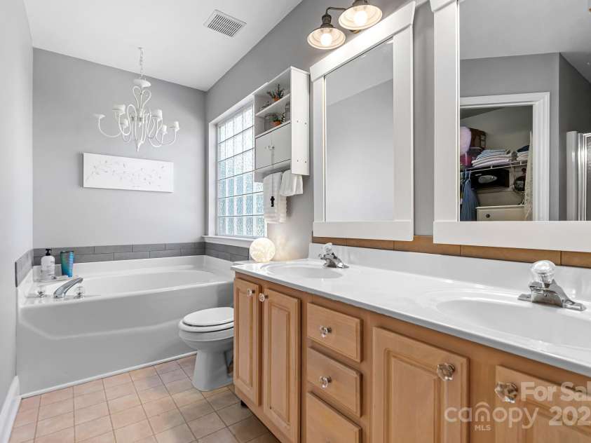 449 Doves Crest Court, Stanley, NC 28164.  MLS# CAR4220525, YatesRealty ID 2672. Dual vanity sinks in the Primary Bathroom with large soaking tub, separate shower and a walk-in closet.