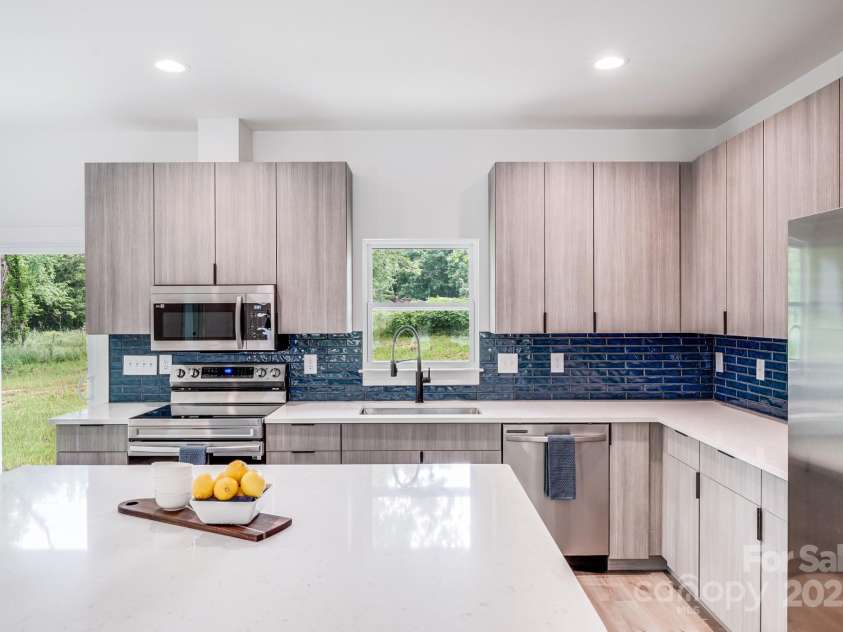 6907 Lancaster Highway, Waxhaw, NC 28173.  MLS# CAR4247480, YatesRealty ID 26742. A beautiful, bold blue tile backsplash adds a vibrant pop of color, perfectly complementing the stainless steel appliances and sleek, understated modern cabinetry.