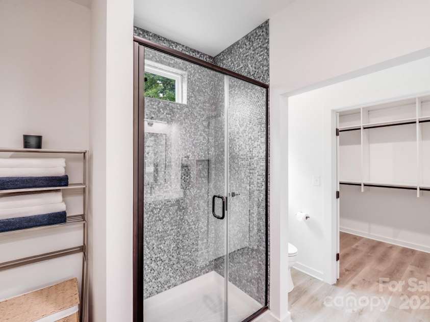6907 Lancaster Highway, Waxhaw, NC 28173.  MLS# CAR4247480, YatesRealty ID 26742. A convenient storage nook, perfect for a hamper and towels, adds functionality to the primary bathroom. The beautiful walk-in shower features custom tile, a glass front, and a high-set window that brings in natural lig